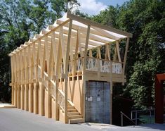 a wooden structure sitting on the side of a road next to some trees and bushes