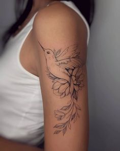 a woman's arm with a bird and flower tattoo on the back of her shoulder