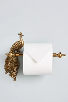 a toilet paper holder with a gold peacock on it and a white envelope in the middle