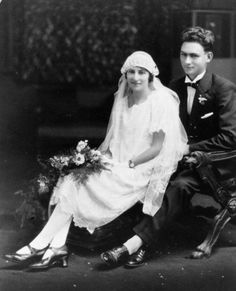 an old black and white photo of a young man and woman in wedding attire sitting next to each other