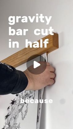 a person holding a wooden bar over a wall with the words gravity bar cut in half