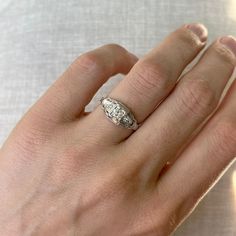 a woman's hand with a diamond ring on top of her left hand,