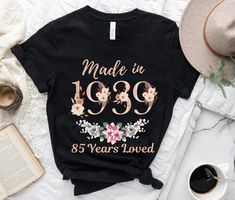 a t - shirt that reads made in 1939 and has flowers on it, next to an open book