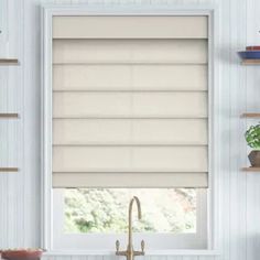 a kitchen with a sink and window covered in roman blind shades on the windowsill