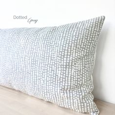 a white and grey pillow sitting on top of a wooden floor next to a wall