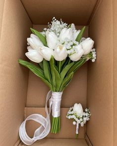 a bouquet of white tulips and baby's breath in a cardboard box