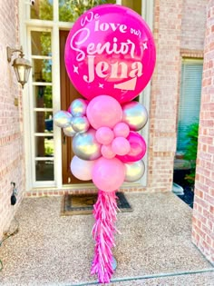 a pink and silver balloon with the words love you jenny written on it in front of a brick building