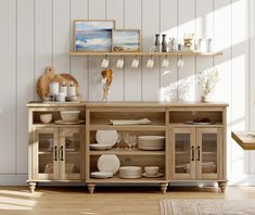 a wooden cabinet with plates and cups on it in front of a white painted wall