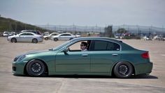 a man sitting in the driver's seat of a green car on an airport tarmac