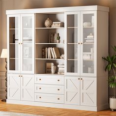 a large white bookcase with glass doors and drawers in the middle of a room