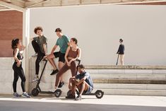 group of young people standing next to each other on scooters in front of a building