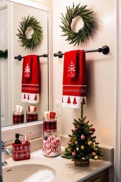 a bathroom decorated for christmas with red and white towels hanging on the wall next to a tree