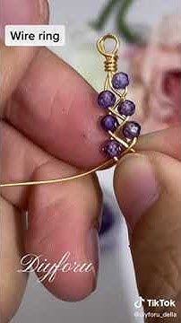 a person is holding a wire ring with purple beads on it and the words wire ring written in gold