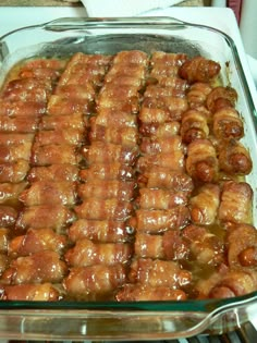 a large glass dish filled with meat wrapped in sauce and sitting on top of a stove