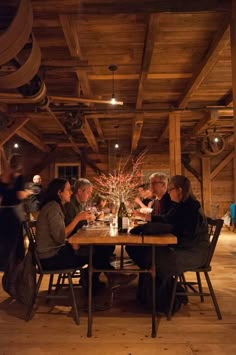 several people sitting at a table in a room with wood beams and exposed ceilinging