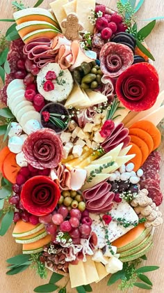 an assortment of cheeses, meats and vegetables arranged in the shape of a heart