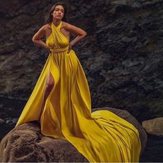 a woman in a yellow dress standing on some rocks