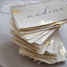 a stack of folded cards with gold foil on them that say naddinee and are sitting on top of each other