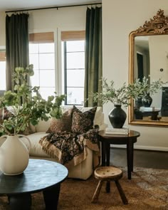 a living room filled with lots of furniture and plants in vases on top of tables