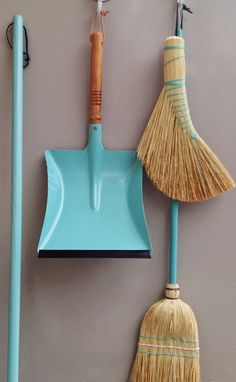 two brooms and a dustpan hanging on the wall