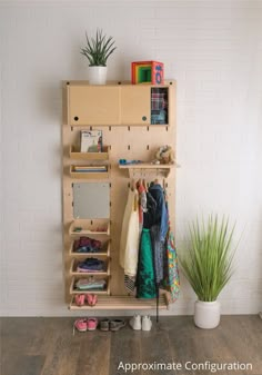 a wooden closet with clothes and shoes on the floor next to a potted plant