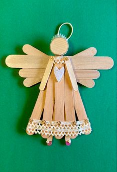 a wooden angel ornament hanging on a green background with lace trimmings