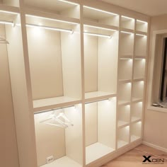 an empty closet with white shelves and lights