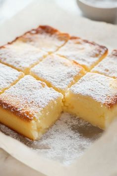 several pieces of cake sitting on top of a piece of wax paper covered in powdered sugar