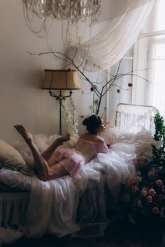 a woman laying on top of a bed next to a chandelier