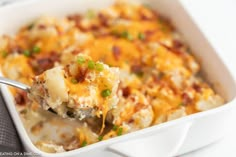 a casserole dish with potatoes and bacon is being held up by a fork