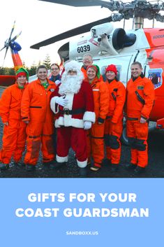 santa clause standing in front of a helicopter with children wearing orange jumpsuits next to him