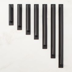 five black handles are lined up on a white surface