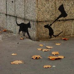 two cats and a dog are painted on the side of a stone wall with leaves scattered around it