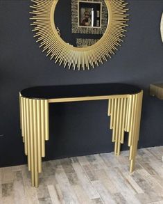 a black and gold console table in front of a wall with a mirror on it