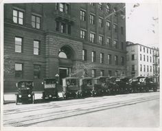 an old black and white photo of train cars parked in front of a large building