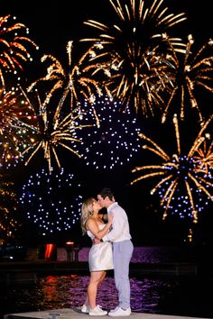 a man and woman kissing in front of fireworks