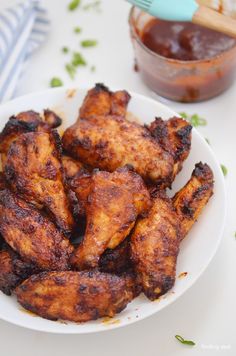 a white plate topped with chicken wings next to a jar of ketchup