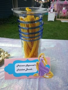 a glass vase filled with yellow pasta noodles next to a sign that reads princess aurora