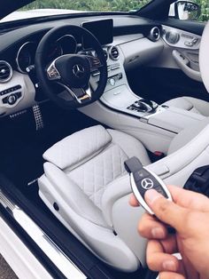 a person holding a remote control in their hand next to a car dashboard and steering wheel