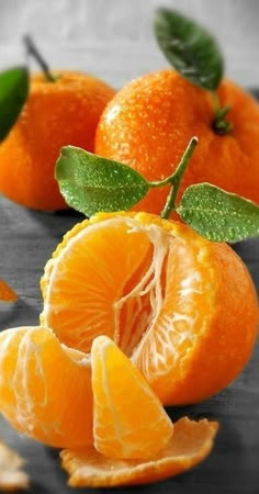 an orange cut in half on a plate with green leaves and water droplets around it