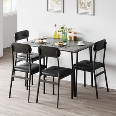 a dining room table with four chairs and plates on the table in front of it