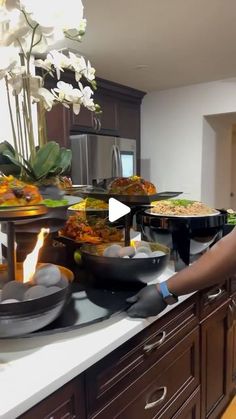 a woman standing in front of a counter filled with plates and bowls full of food