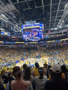 a crowd of people watching a basketball game in a large arena with lots of lights