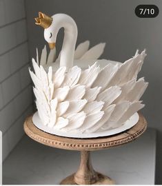 a white swan cake sitting on top of a wooden stand