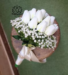 a bouquet of white tulips and baby's breath on a wooden stand