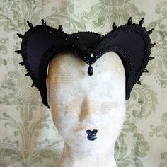 This is a purple and black version of one of most successful designs called Countess. This vampire style headdress is covered with dark purple taffeta and embellished with black cord trimming all around the edges.It is further trimmed with black crystal details that create a halo effect as well as small l beads that were hand-sewn on the trimming to create rich textural interest. The piece is completed with a black crystal handmade element placed at the center front for all that extra drama that Fitted Black Gothic Costume, Fantasy Purple Costume For Costume Party, Fantasy Costume For Costume Party In Purple, Fitted Black Costume For Alternative Fashion, Black Fitted Costumes For Alternative Fashion, Black Fitted Costume For Alternative Fashion, Black Fitted Gothic Costume, Medieval Costumes For Party And Cosplay Events, Gothic Headpiece For Masquerade And Cosplay Events