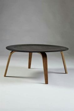 an oval coffee table with wooden legs and a black top, on a white background