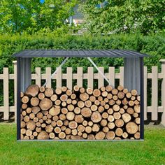 a pile of logs sitting in front of a wooden fence