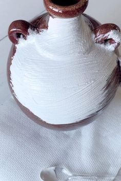 a brown and white vase sitting on top of a table next to a white cloth