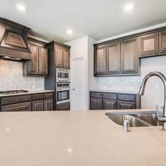 a large kitchen with wooden cabinets and stainless steel appliances in the center, along with marble counter tops